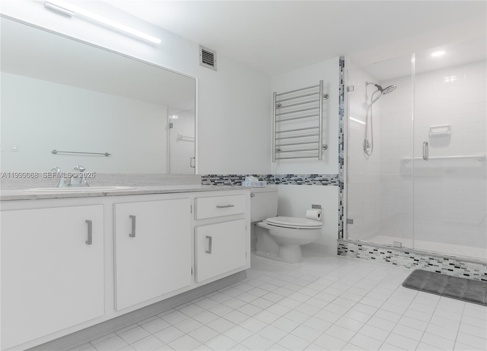 A white bathroom features a vanity, a toilet, and a glass-enclosed walk-in shower — 500 Three Islands Blvd # 1110, Hallandale Beach FL 33009, HALLANDALE BEACH, FL