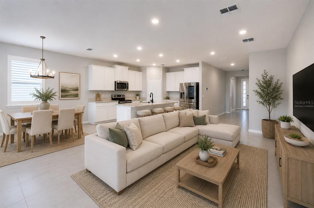 An open-concept living room and kitchen featuring white cabinetry, a large sectional, and dining area — 1215 OCEAN SPRAY DRIVE, RUSKIN, FL