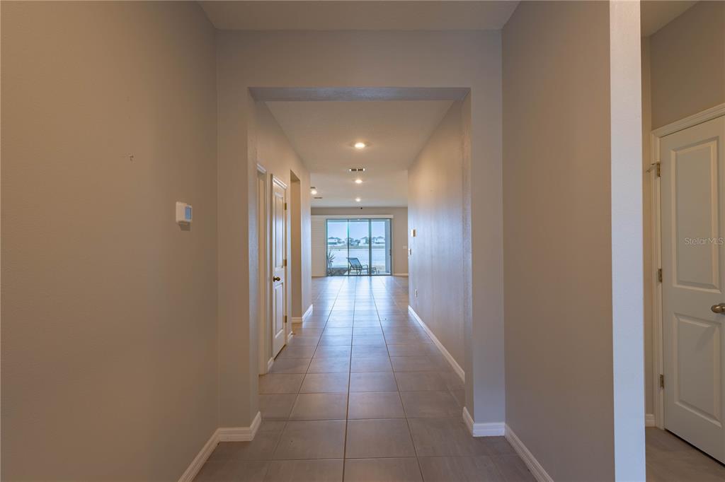A tiled hallway leads from the entrance toward a living area with sliding glass doors — 1215 OCEAN SPRAY DRIVE, RUSKIN, FL