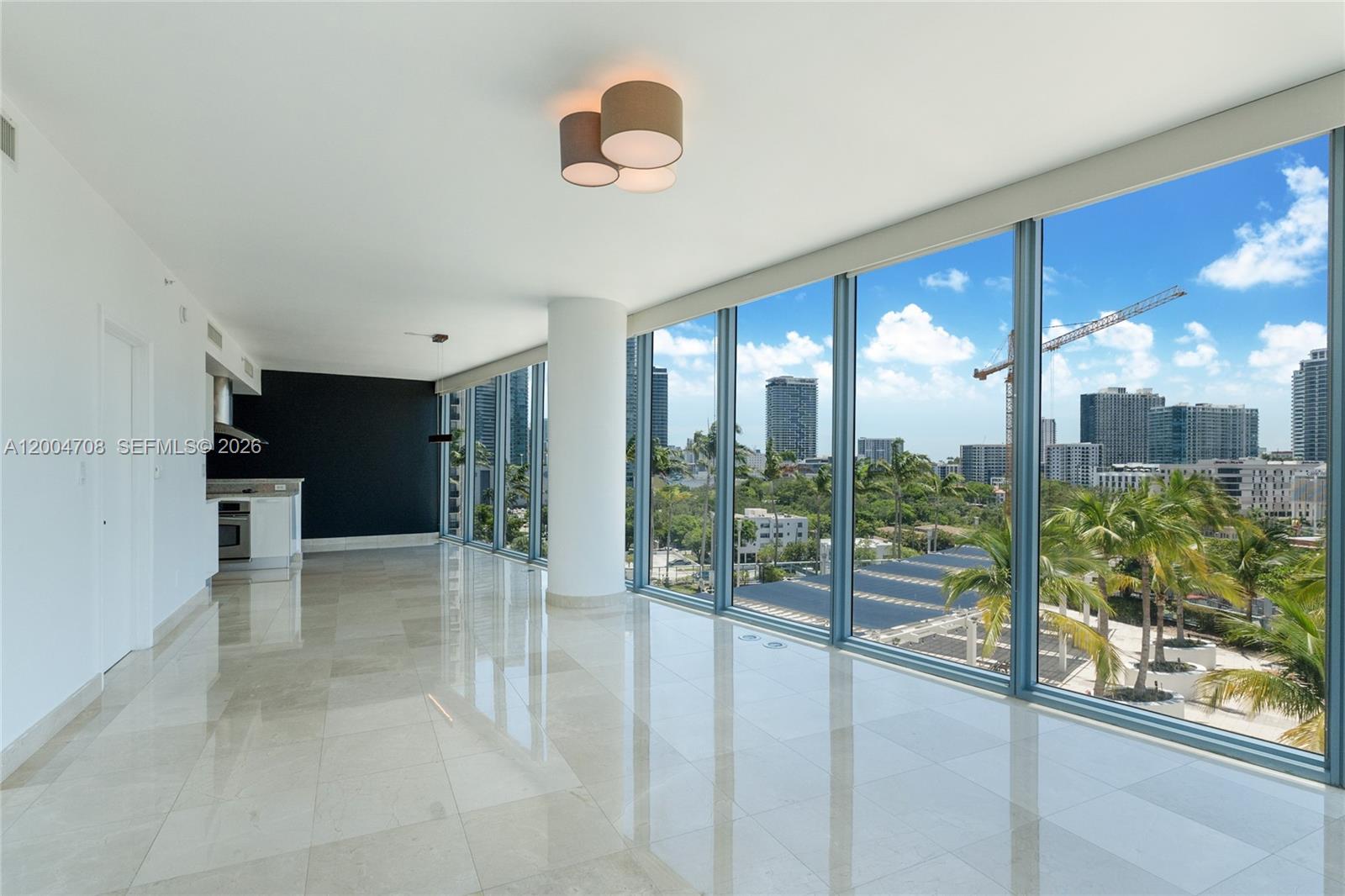 An open-concept living area features floor-to-ceiling windows, tile flooring, and a view of city construction — 601 NE 36th St # 801, Miami FL 33137, MIAMI, FL