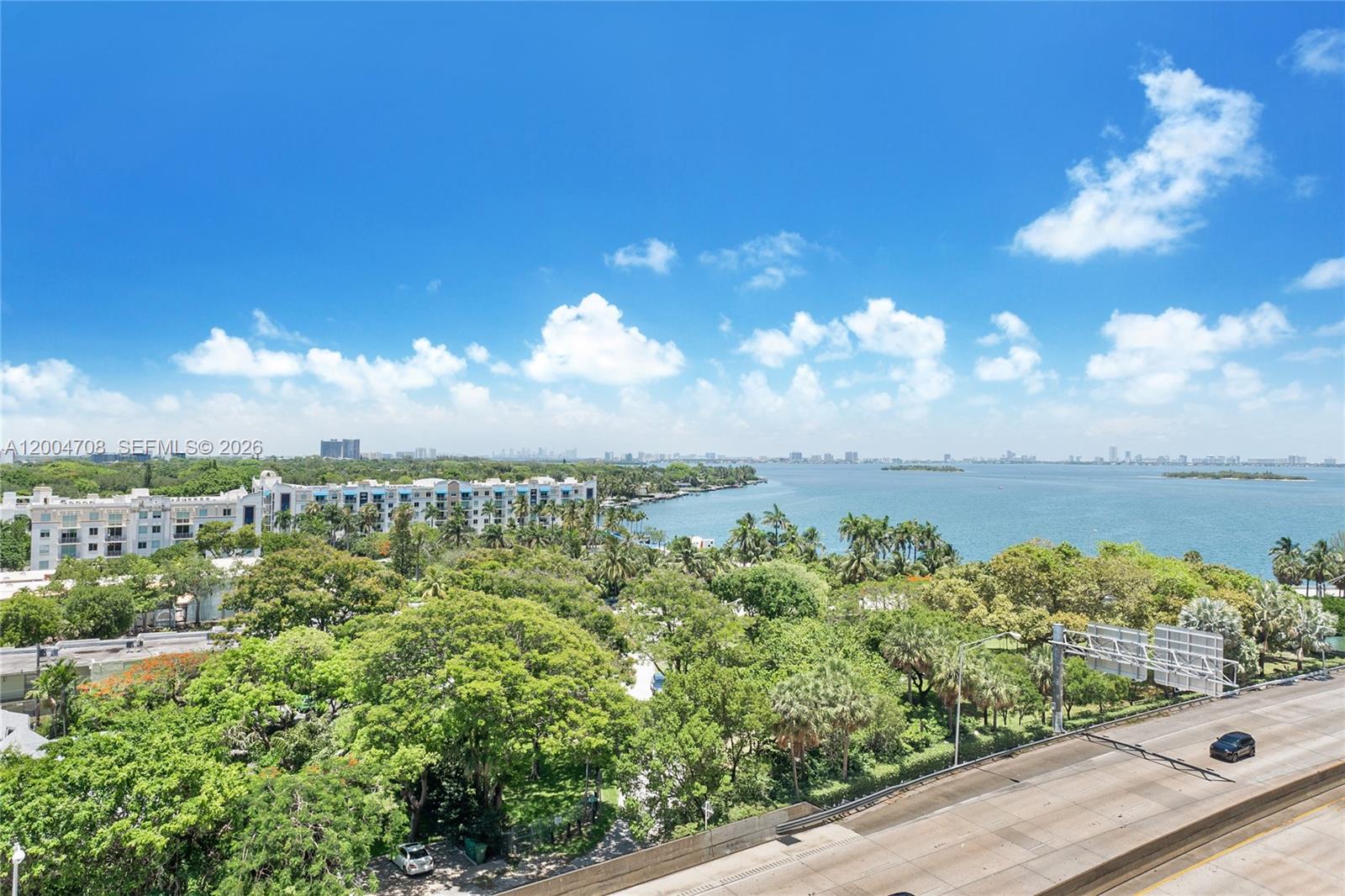 An elevated view shows a highway, dense green trees, a waterfront apartment complex, and bay — 601 NE 36th St # 801, Miami FL 33137, MIAMI, FL