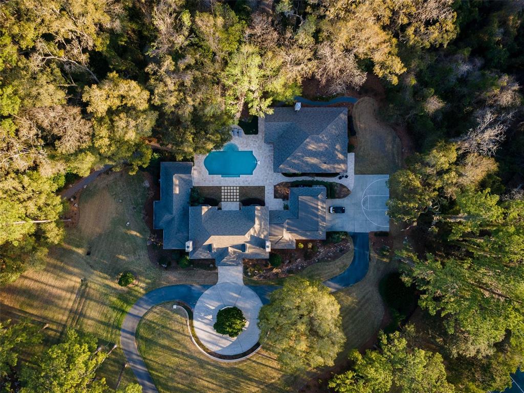 An aerial view shows a large house with a circular driveway, pool, and basketball court — 623 SW 93RD STREET, GAINESVILLE, FL