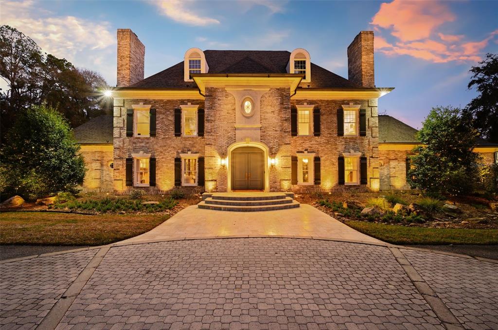 A two-story brick house with a paved driveway and symmetrical windows at dusk — 623 SW 93RD STREET, GAINESVILLE, FL