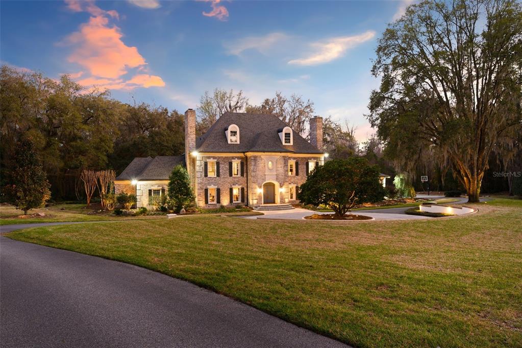 A two-story stone house with a circular driveway sits on a large, grassy lot — 623 SW 93RD STREET, GAINESVILLE, FL