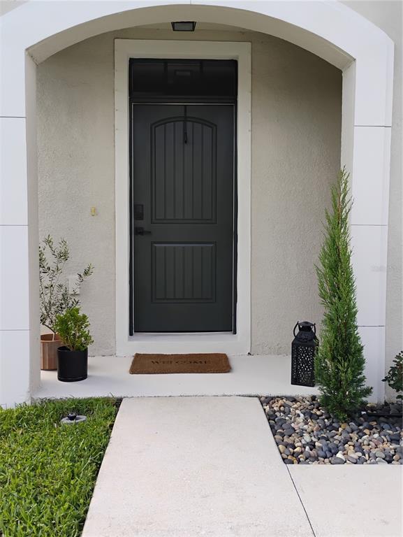 A dark front door with a transom window is centered under a white arched entryway — 5150 SAN PALERMO DRIVE, BRADENTON, FL