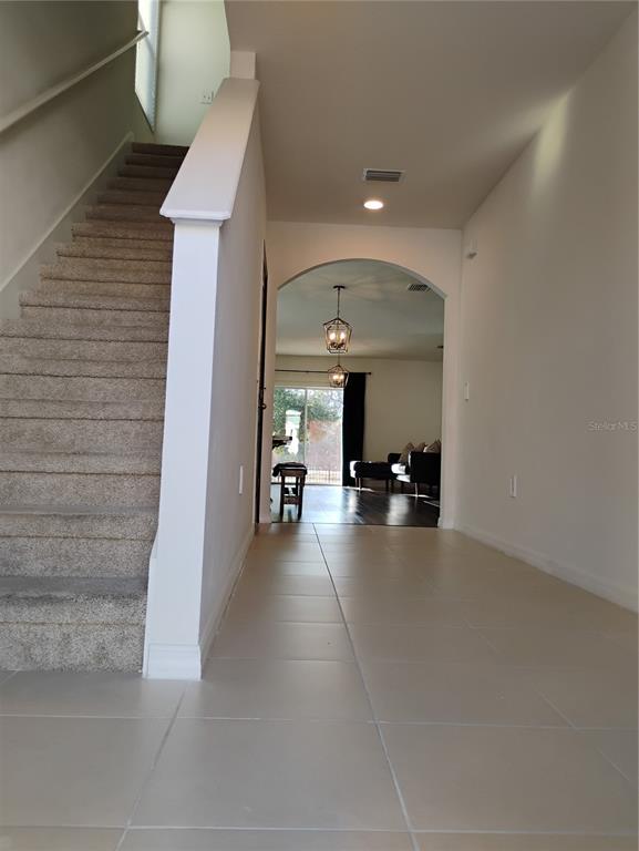 A tiled entryway leads to a carpeted staircase and an arched doorway into a living area — 5150 SAN PALERMO DRIVE, BRADENTON, FL