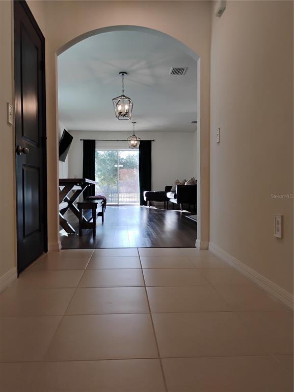 A tiled entryway leads through an arched doorway into a living area with dark flooring — 5150 SAN PALERMO DRIVE, BRADENTON, FL