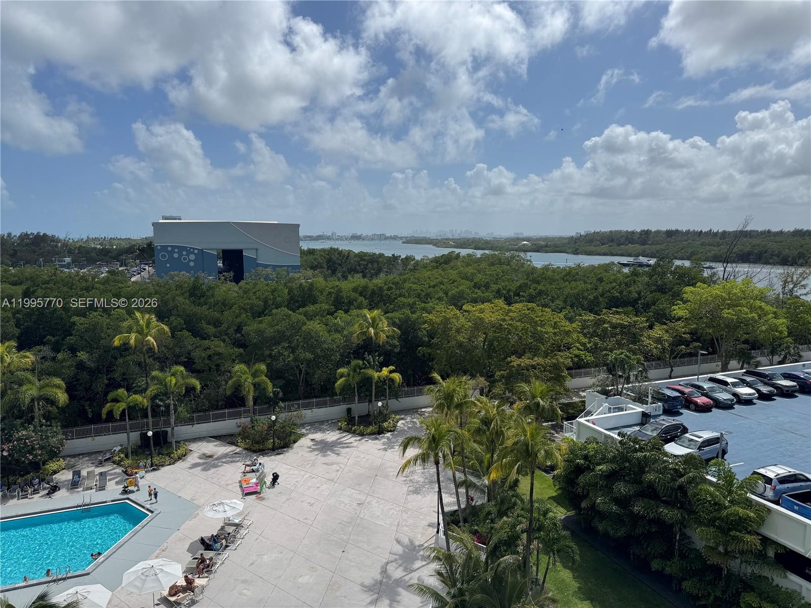 An elevated view shows a swimming pool, palm trees, a parking lot, and a waterway — 100 Bayview Dr # 725, Sunny Isles Beach FL 33160, SUNNY ISLES BEACH, FL