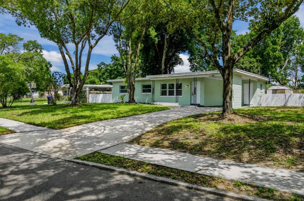 A single-story, light green house with a carport and a large tree in the yard — 1435 EDEN DRIVE, APOPKA, FL