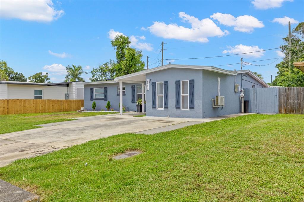A single-story gray house with a concrete driveway, a covered porch, and dark blue shutters — 9780 53RD STREET N, PINELLAS PARK, FL