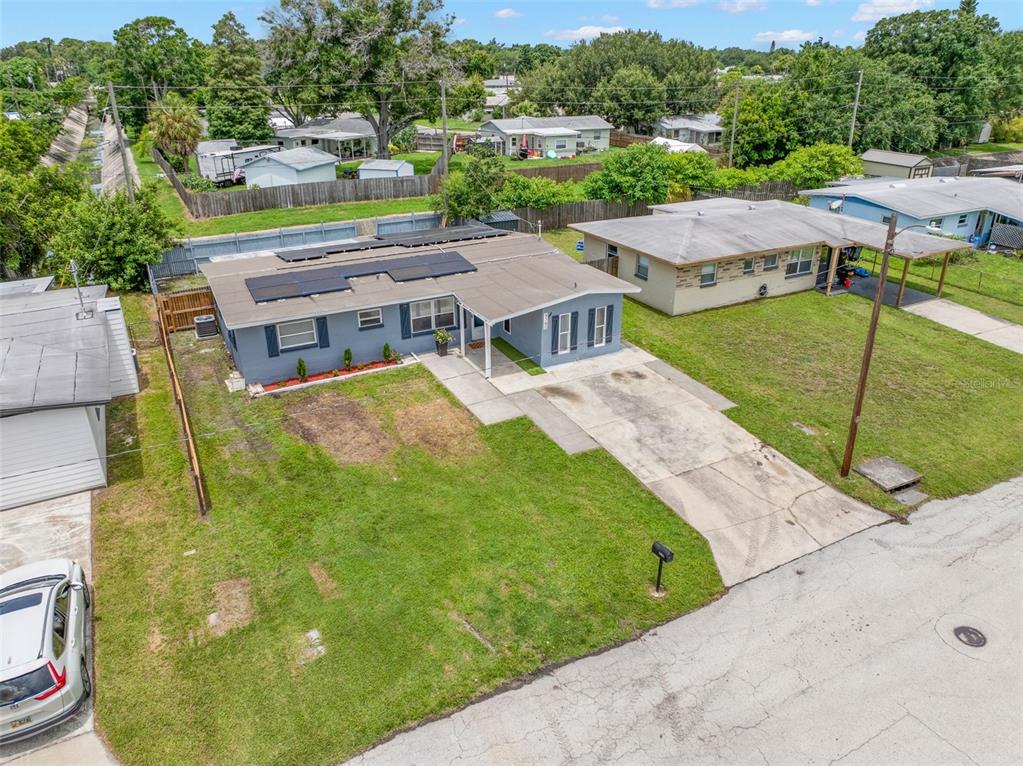 An aerial view shows a blue single-story house with solar panels and a concrete driveway — 9780 53RD STREET N, PINELLAS PARK, FL