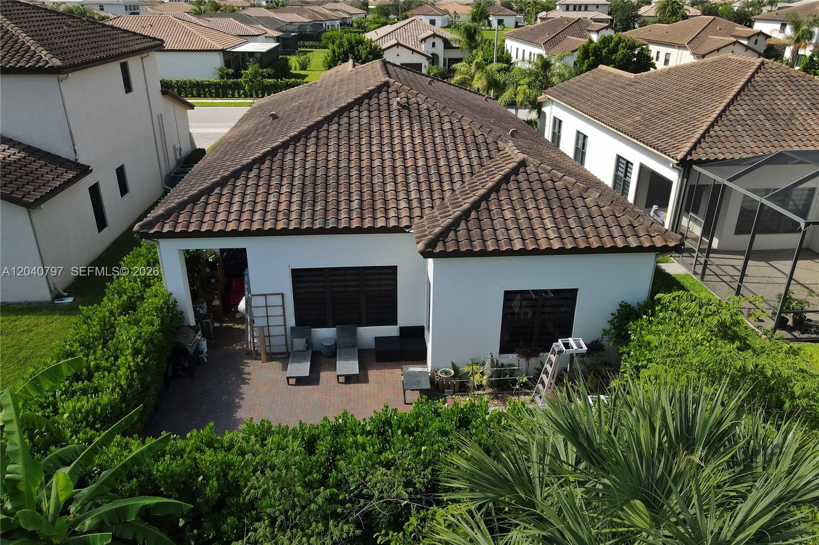 An aerial view shows the backyard patio and tiled roof of a white suburban house — 4742 Corrado Ave, Ave Maria FL 34142, AVE MARIA, FL