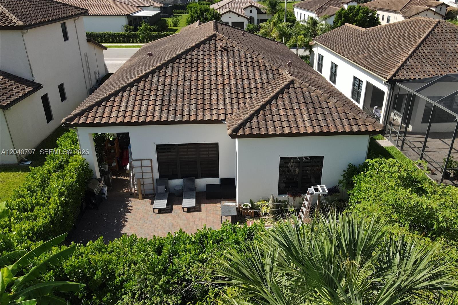 An aerial view shows the back patio and tiled roof of a white suburban house — 4742 Corrado Ave, Ave Maria FL 34142, AVE MARIA, FL