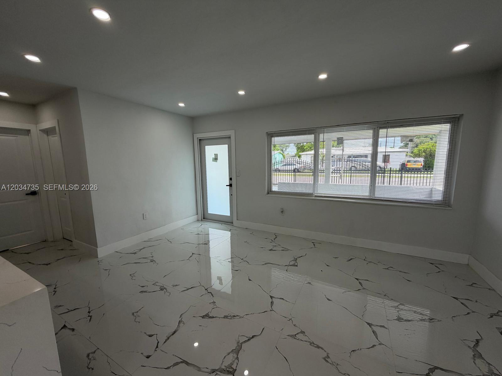 A bright room features white marble-patterned tile flooring, recessed lighting, and a large window — 2800 NW 164th St, Miami Gardens FL 33054, MIAMI GARDENS, FL