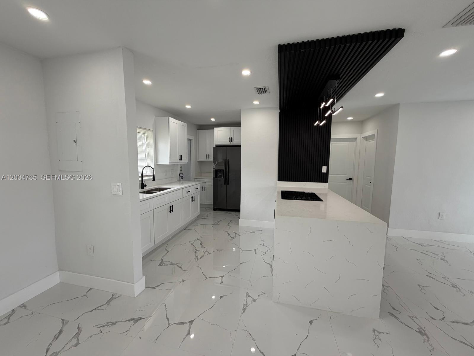 A modern kitchen features white cabinets, a marble-patterned island, and a black slatted ceiling accent — 2800 NW 164th St, Miami Gardens FL 33054, MIAMI GARDENS, FL