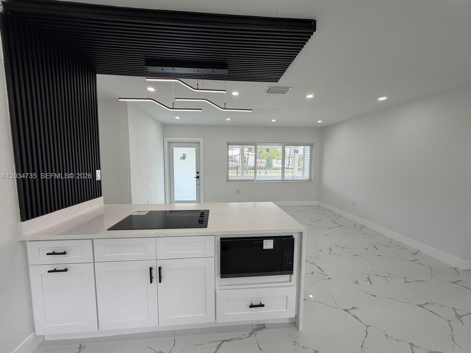 A modern kitchen features white cabinets, a marble-patterned countertop, and a black slatted ceiling accent — 2800 NW 164th St, Miami Gardens FL 33054, MIAMI GARDENS, FL