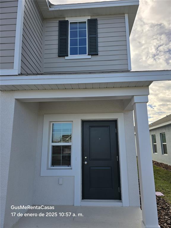 The exterior of a two-story house features a covered entryway, a dark door, and siding — 5794 LE MARIN WAY, KISSIMMEE, FL