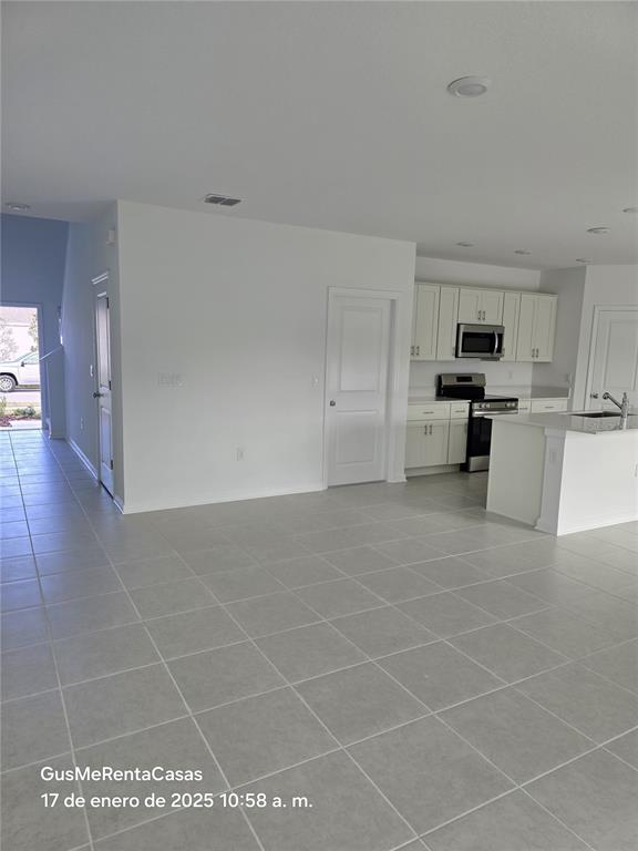 A bright, open-concept kitchen and living area features white cabinetry, tile flooring, and recessed lighting — 5794 LE MARIN WAY, KISSIMMEE, FL