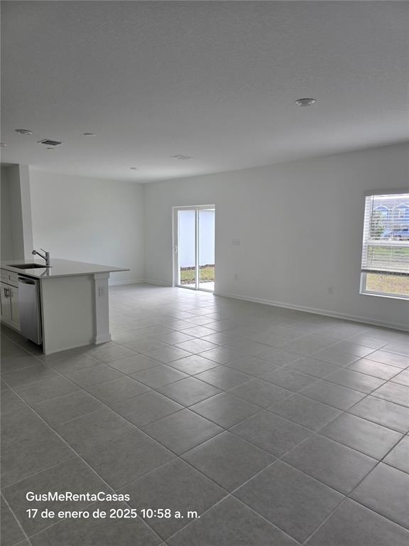 A bright, open-concept kitchen and living area features light gray tile flooring and white walls — 5794 LE MARIN WAY, KISSIMMEE, FL