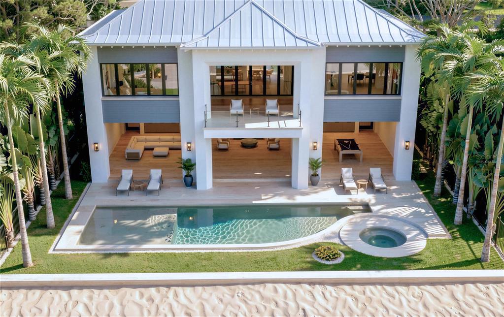 A modern outdoor courtyard features a seating area with a sofa, chairs, and a rug — 620 GULF BOULEVARD, BELLEAIR SHORE, FL