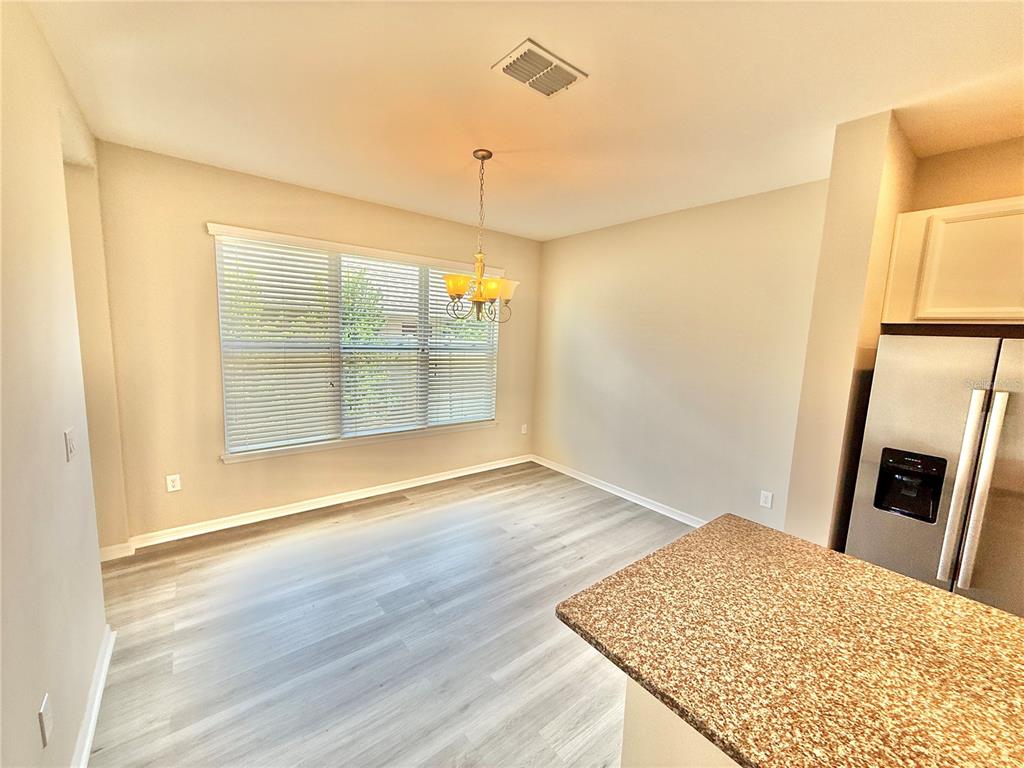 A dining area with light wood-look flooring, a chandelier, and a window with blinds — 11686 WATER RUN ALLEY, WINDERMERE, FL