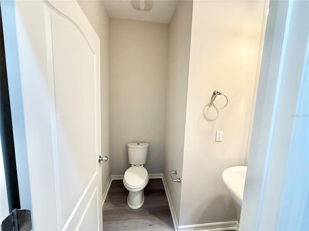 A small bathroom features a toilet, a pedestal sink, and light gray walls — 11686 WATER RUN ALLEY, WINDERMERE, FL