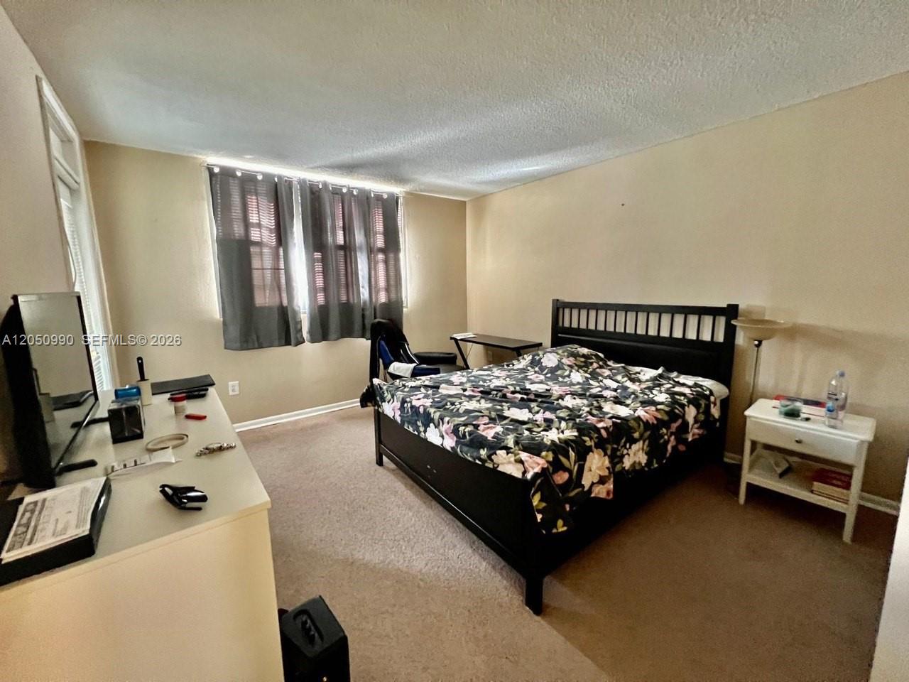 A bedroom features a black bed frame, a white dresser, and a window with curtains — 1700 NE 191st St # 508, Miami FL 33179, MIAMI, FL