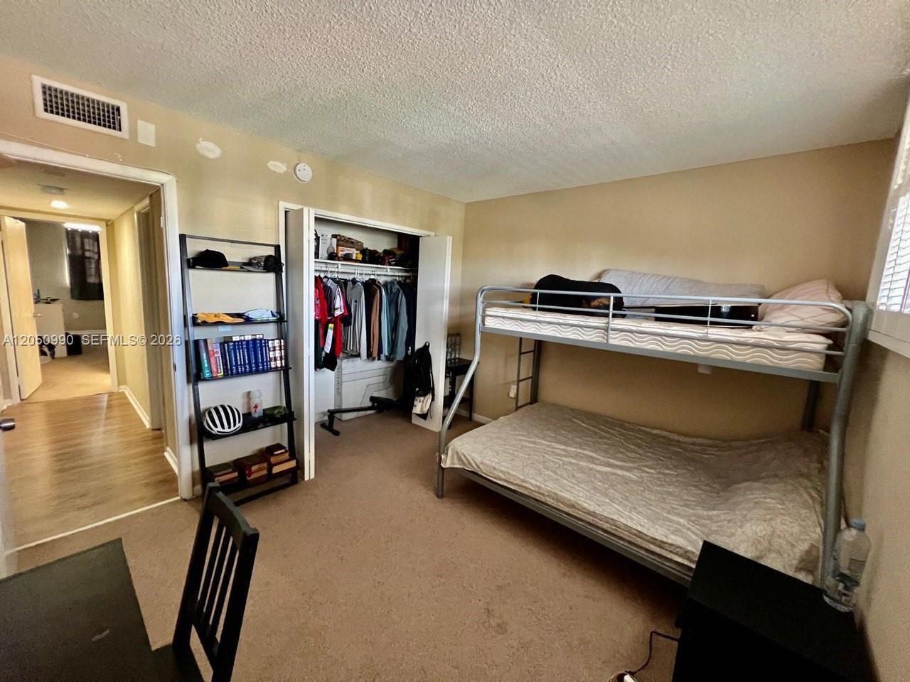 A bedroom features a metal bunk bed, an open closet, and a tall shelving unit — 1700 NE 191st St # 508, Miami FL 33179, MIAMI, FL