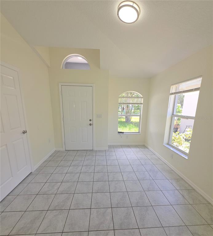 An entryway with light-colored tile flooring, a white door, and two windows — 6109 GEORGIA AVENUE, NEW PORT RICHEY, FL