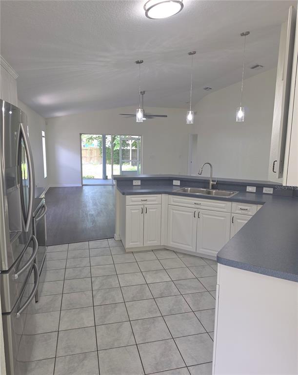 A kitchen with white cabinets, blue countertops, and tile flooring overlooks an open living area — 6109 GEORGIA AVENUE, NEW PORT RICHEY, FL