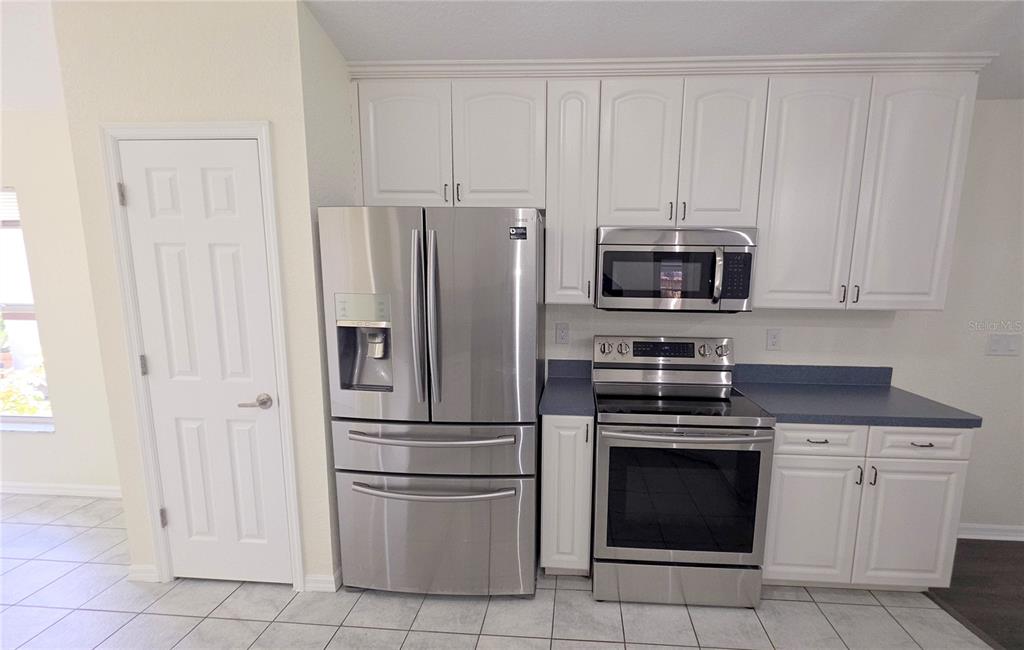 A kitchen features white cabinetry, stainless steel appliances, and a blue countertop — 6109 GEORGIA AVENUE, NEW PORT RICHEY, FL