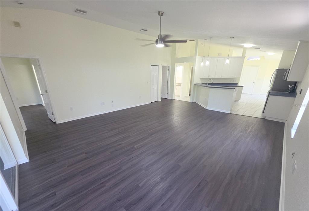 An open-concept living area features dark wood-look flooring, a ceiling fan, and an adjacent kitchen — 6109 GEORGIA AVENUE, NEW PORT RICHEY, FL