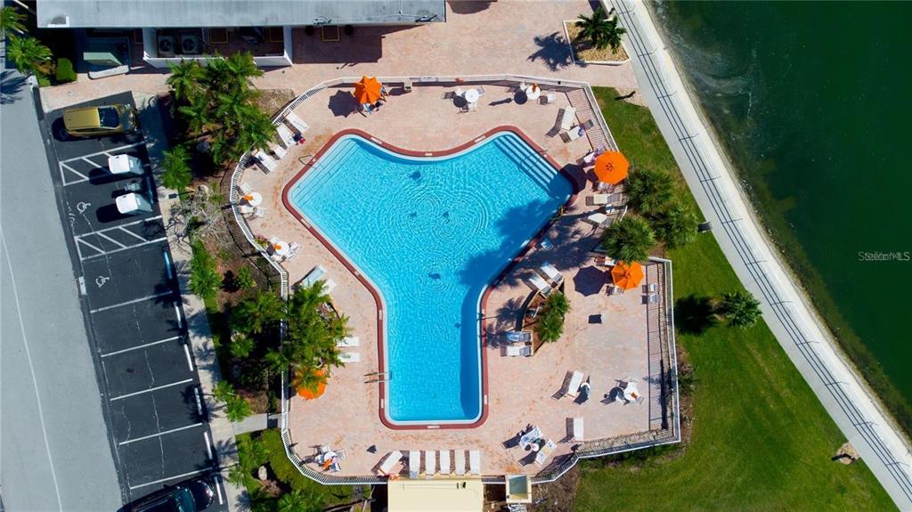 An aerial view shows a Y-shaped swimming pool surrounded by a patio and parking lot — 4550 COVE CIRCLE UNIT 106, ST PETERSBURG, FL