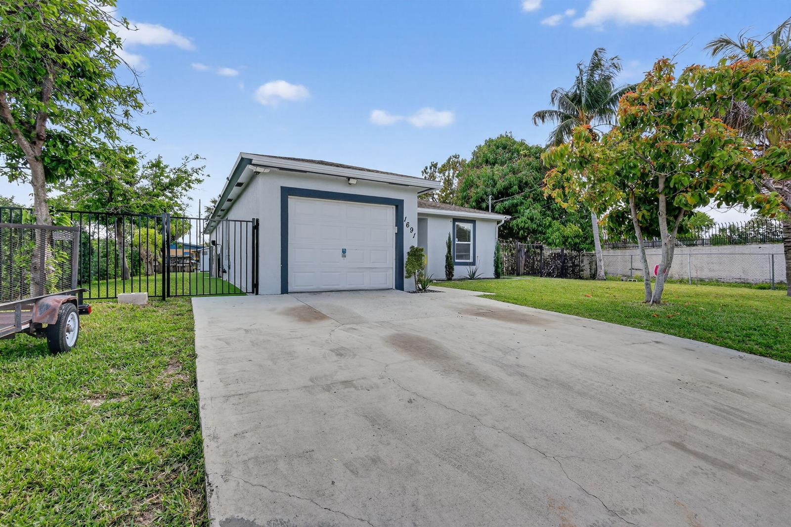 A single-story house with a white exterior, a garage, and a concrete driveway — 1691 W 26th Court, Riviera Beach FL 33404, RIVIERA BEACH, FL