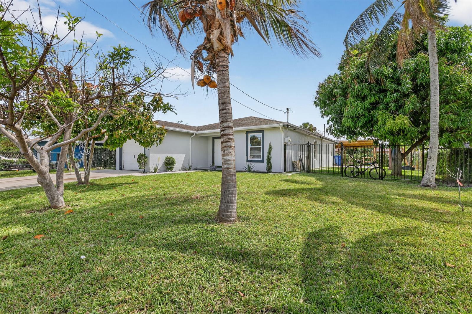 A single-story house with a gray exterior, a palm tree, and a black metal fence — 1691 W 26th Court, Riviera Beach FL 33404, RIVIERA BEACH, FL