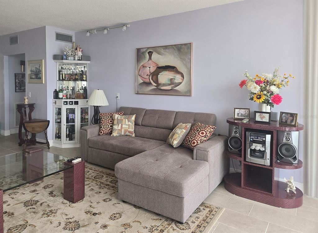 A living room features a gray sectional sofa, a glass coffee table, and a corner bar — 7100 SUNSHINE SKYWAY LANE S UNIT 503, ST PETERSBURG, FL