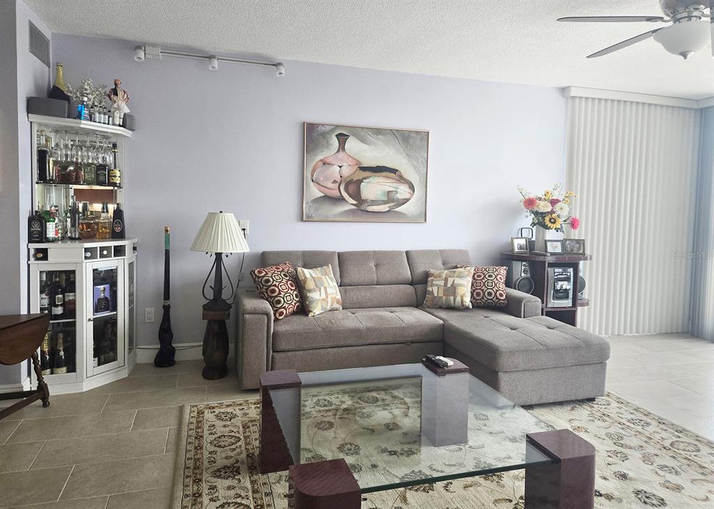 A living room features a gray sectional sofa, a glass coffee table, and a corner bar — 7100 SUNSHINE SKYWAY LANE S UNIT 503, ST PETERSBURG, FL