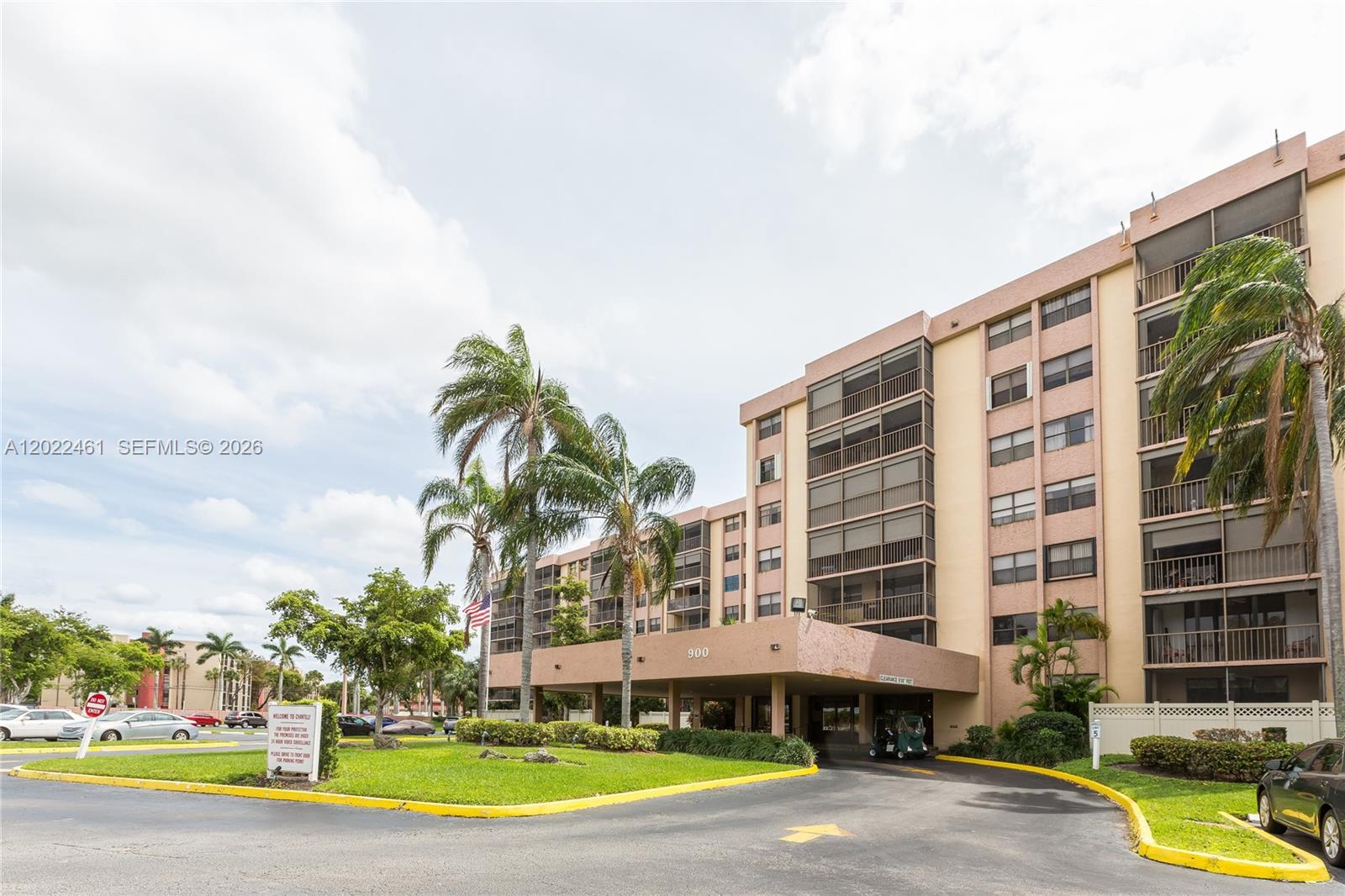 A multi-story apartment building with a covered entrance and palm trees in the foreground — 900 NE 195th St # 618, Miami FL 33179, MIAMI, FL