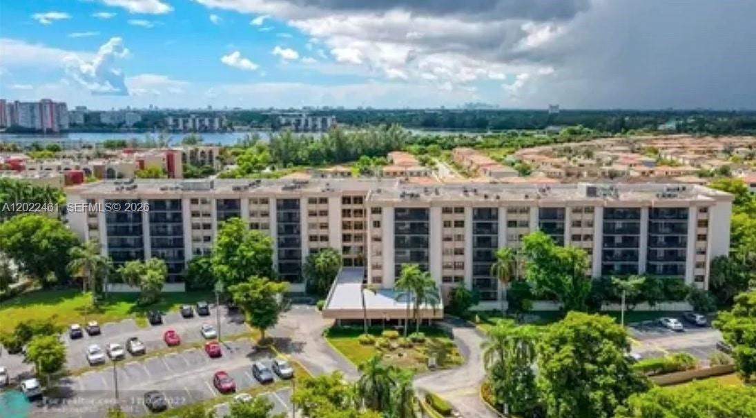 An aerial view shows a multi-story apartment building surrounded by trees and a parking lot — 900 NE 195th St # 618, Miami FL 33179, MIAMI, FL
