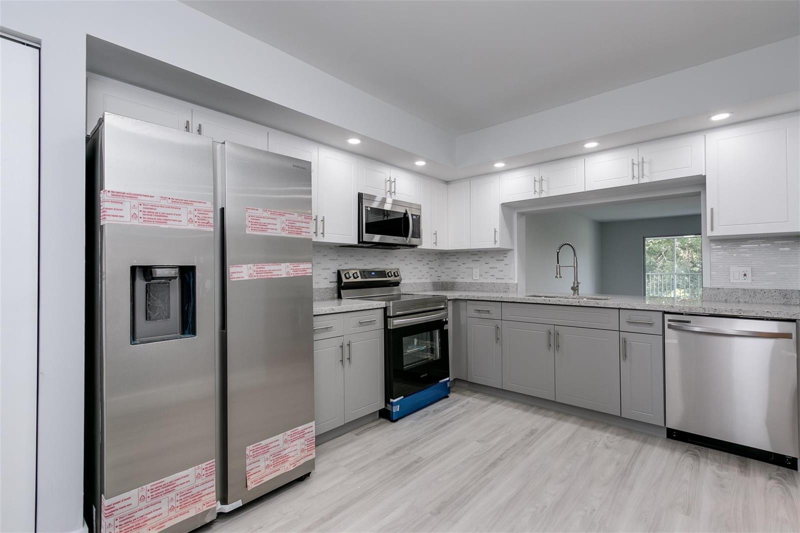 A kitchen with stainless steel appliances, white upper cabinets, gray lower cabinets, and granite countertops — 12600 SW 5th Court # 408l, Pembroke Pines FL 33027, PEMBROKE PINES, FL