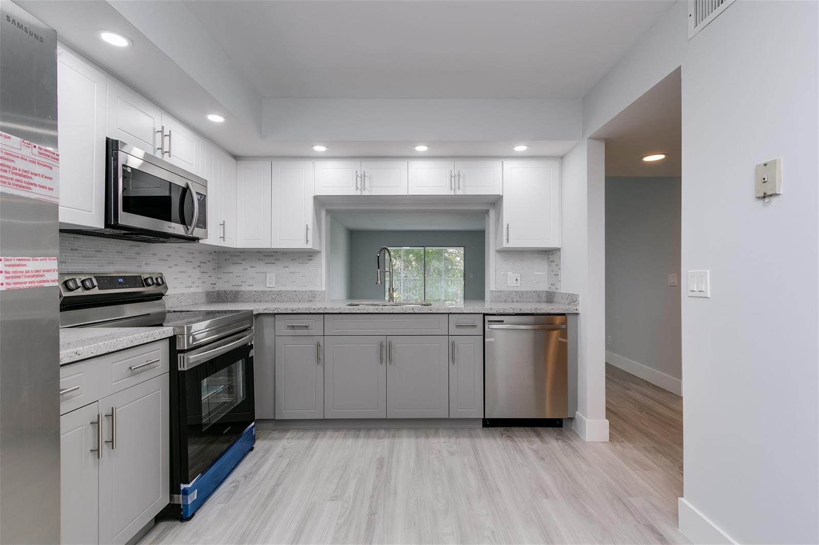 A modern kitchen features white upper cabinets, gray lower cabinets, stainless steel appliances, and countertops — 12600 SW 5th Court # 408l, Pembroke Pines FL 33027, PEMBROKE PINES, FL
