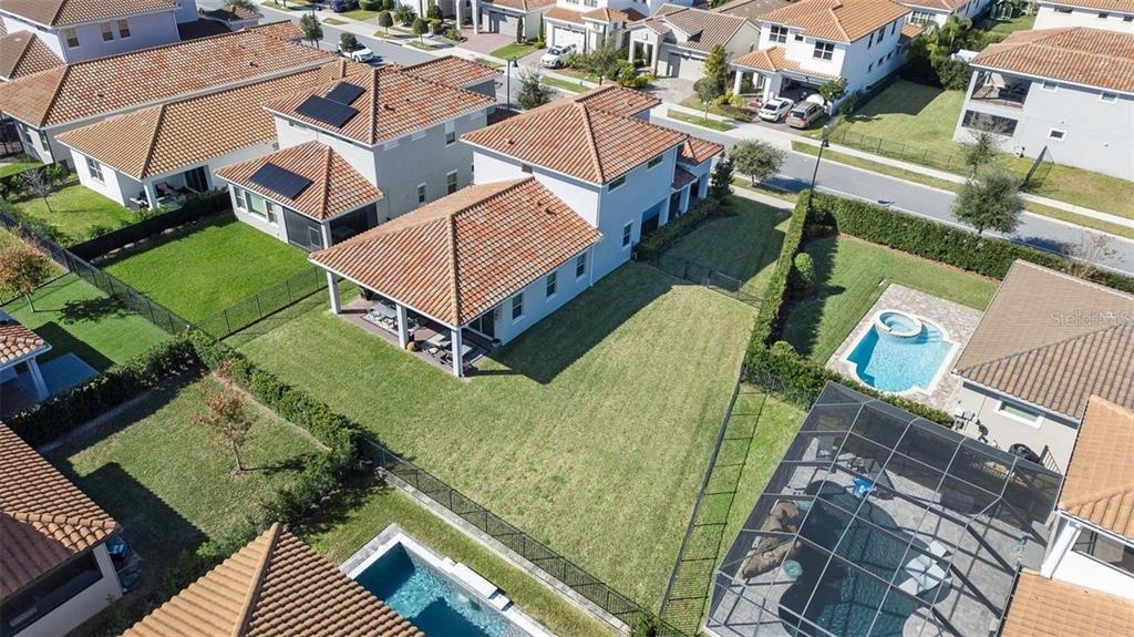 An aerial view shows several suburban houses with tiled roofs, private swimming pools, and fenced backyards — 10562 GATLEY PLACE, ORLANDO, FL
