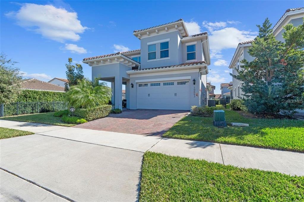 A two-story suburban house features a brick driveway, a two-car garage, and a tiled roof — 10562 GATLEY PLACE, ORLANDO, FL