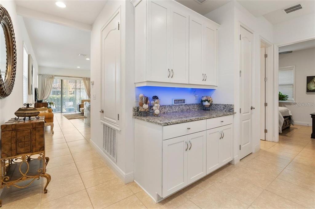 A white cabinet unit with granite countertops and blue under-cabinet lighting sits in a hallway — 10562 GATLEY PLACE, ORLANDO, FL