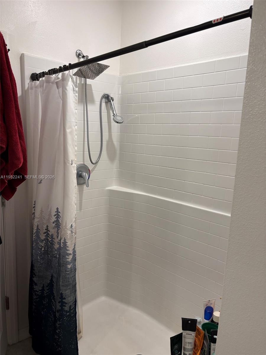 A shower stall features white subway tile walls, a rain showerhead, and a handheld sprayer — 8065 97th Ave, Vero Beach FL 32967, VERO BEACH, FL