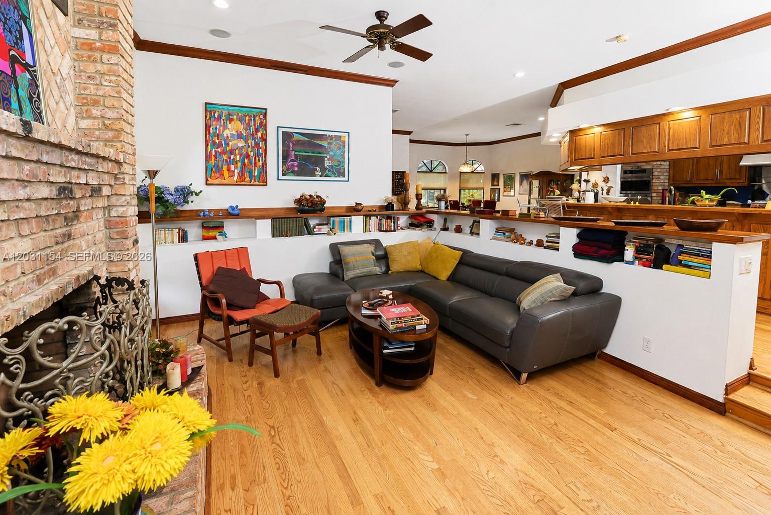 A living room features a brick fireplace, hardwood floors, a sectional sofa, and built-in shelving — 5440 Shady Oak Ln, Dania Beach FL 33312, DANIA BEACH, FL