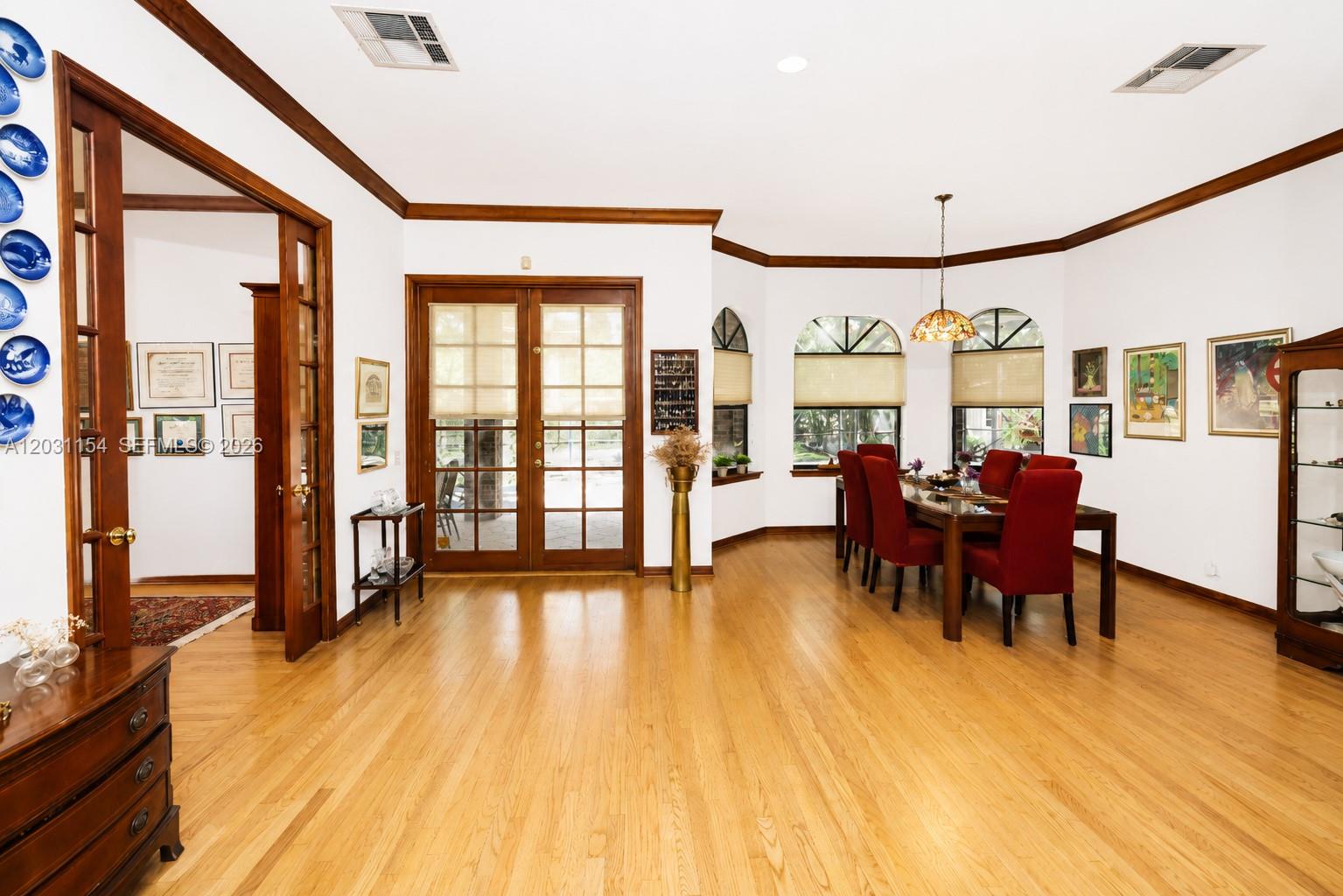 A dining room features hardwood floors, red chairs, a wooden table, and glass-paned French doors — 5440 Shady Oak Ln, Dania Beach FL 33312, DANIA BEACH, FL