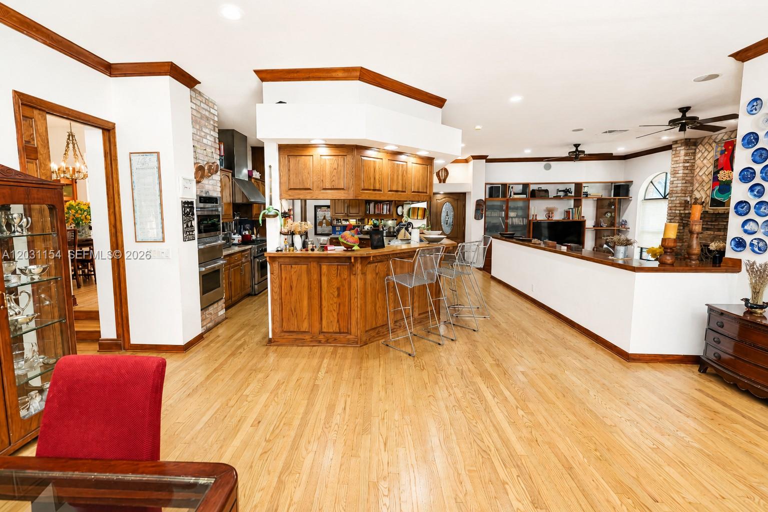 A kitchen with wood cabinets and a breakfast bar opens into a living area — 5440 Shady Oak Ln, Dania Beach FL 33312, DANIA BEACH, FL