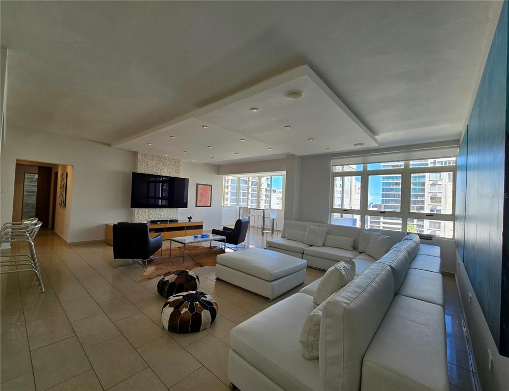 A modern living room features a large white sectional sofa, tile flooring, and floor-to-ceiling windows — 1160 MAGDALENA AVENUE UNIT 7B, SAN JUAN, PR