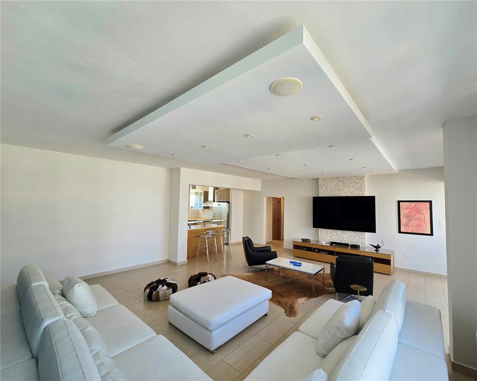 A spacious living room features a white sectional sofa, a drop ceiling, and a television — 1160 MAGDALENA AVENUE UNIT 7B, SAN JUAN, PR